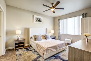 A bedroom with a bed, nightstand, and a ceiling fan.